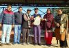 Social activist K K Wadhera, flanked by Principal Anuradha, and staff handing over cloth bags to a student at GHSS Bahu Fort in Jammu.