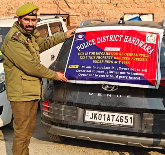 A police official pasting attachment notice on a vehicle allegedly used in drug trafficking in Handwara on Tuesday. A police official pasting attachment notice on a vehicle allegedly used in drug trafficking in Handwara on Tuesday.