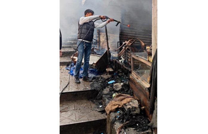 A fire-fighter dousing flames to control fire at shops in Charan Paduka area of Katra. - Excelsior/Romesh Mengi A fire-fighter dousing flames to control fire at shops in Charan Paduka area of Katra. - Excelsior/Romesh Mengi