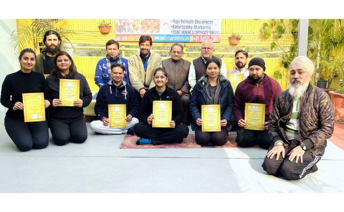 Newly certified Yoga teachers posing along with certificates and instructors.