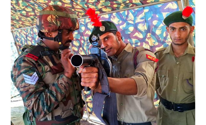 A student aiming while holding a medium gun during weapon display in Balakote area of Poonch.