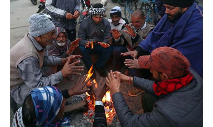 People sitting around a bonfire to warm themselves on the outskirts of Jammu. -Excelsior/Rakesh