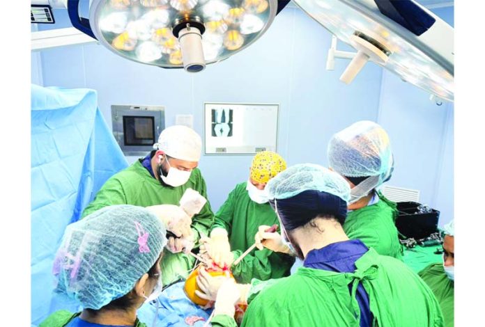 A team of doctors performing total knee replacement surgery on a patient at AIIMS Jammu.