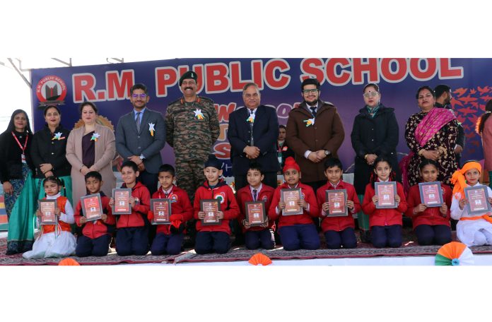 Students displaying certificates while posing along with dignitaries during school foundation day.