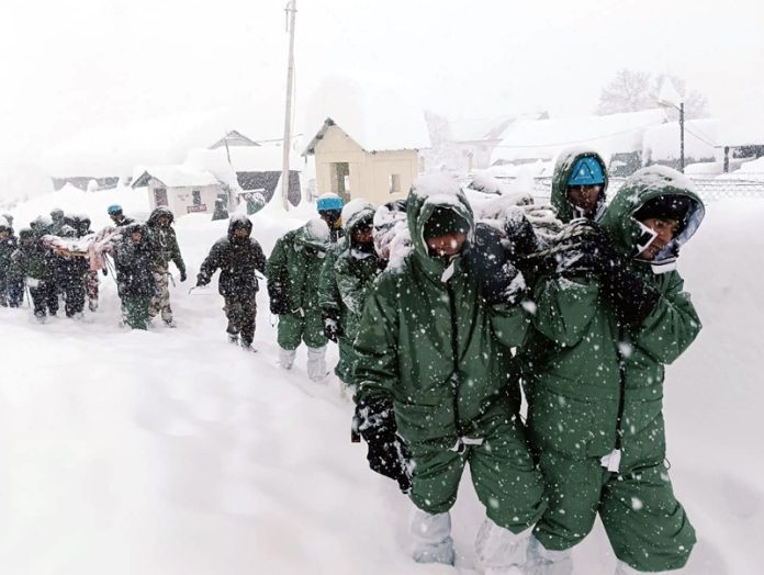 Army rescue team carrying injured workers trapped during an avalanche in Chamoli district on way to Badrinath. (UNI)