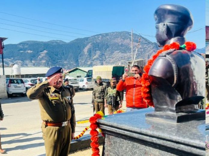 A Police officer saluting before the bust of martyr, DySP Aman Thakur in Kishtwar on Monday. —Excelsior/Tilak Raj