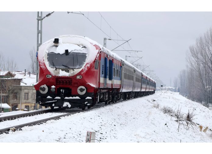 Train chugs along the Srinagar-Baramulla track amid snowfall in Srinagar on Friday morning. — Excelsior/Shakeel