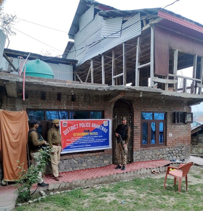Police attaching property in Anantnag on Friday.