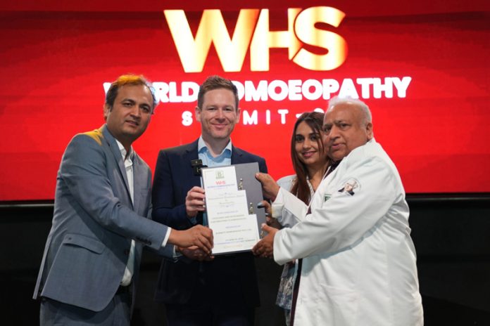 Dr Shakti Dhar Sharma receiving award from ex-English cricket captain, Eon Morgan at World Homeo Summit in Germany.