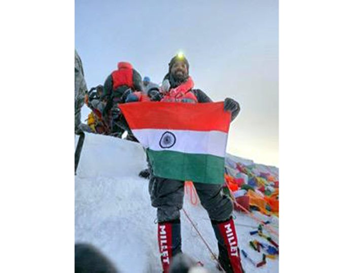 Army Mountaineer posing along with national flag at Mt Everest