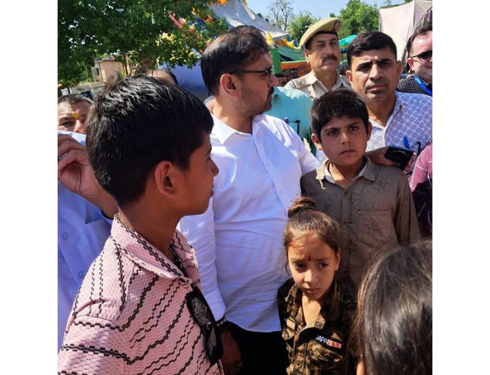 Minister Satish Sharma meeting children at a relief camp on Monday. Minister Satish Sharma meeting children at a relief camp on Monday.