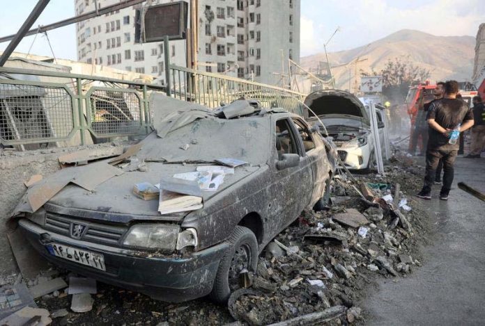People gather near damaged vehicles in the aftermath of Israeli strikes in Tehran on Friday. People gather near damaged vehicles in the aftermath of Israeli strikes in Tehran on Friday.