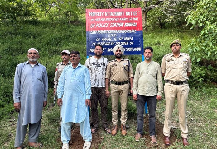 Cops pose for a photograph after fixing a board at the attached property of a terrorist.