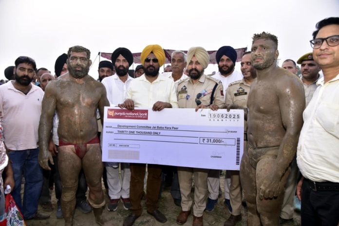 Dignitaries presenting a cheque to winner wrestlers during a programme. Dignitaries presenting a cheque to winner wrestlers during a programme.