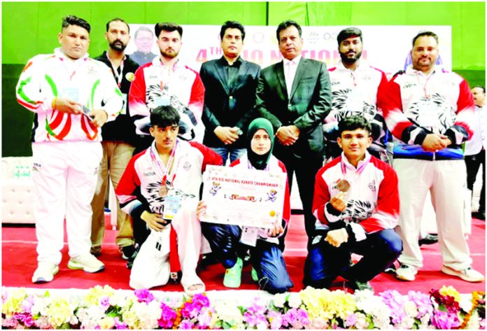 Karate players posing along with medals alongside dignitaries.