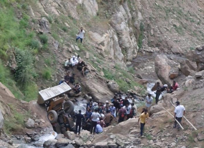 Rescuers and others standing near a JCB vehicle which plunged into a gorge in Dachan area of Kishtwar on Tuesday. Rescuers and others standing near a JCB vehicle which plunged into a gorge in Dachan area of Kishtwar on Tuesday.