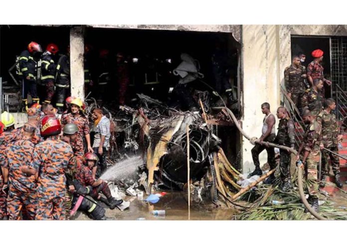 Firefighters and army members work next to the wreckage of an air force training aircraft after it crashed into Milestone College campus, in Dhaka, Bangladesh on Monday.