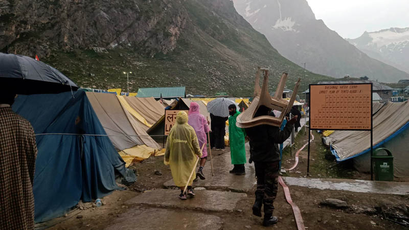 Strong winds and heavy rain force Amarnath pilgrims to take cover in tents at Sheshnag halting station on their way to the holy cave shrine in South Kashmir Himalayas on Monday.—Excelsior/Sajad Dar