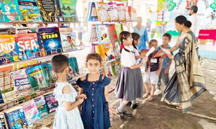 Students and a teacher exploring a wide range of books together during Scholastic Book Fair at APS Damana.