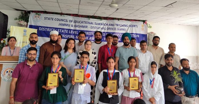 Meritorious students with medals & certificates posing with guests during SCERT event.