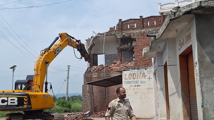 A JCB demolishing the house of an alleged drug peddler in Kathua district on Thursday . -Excelsior/Pardeep