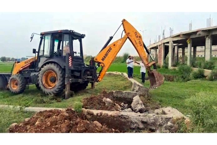 A JCB demolishing an illegal plinth during a demolition drive in Bishnah area on Tuesday.