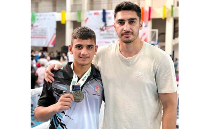 Yasser with his coach displaying his medal.