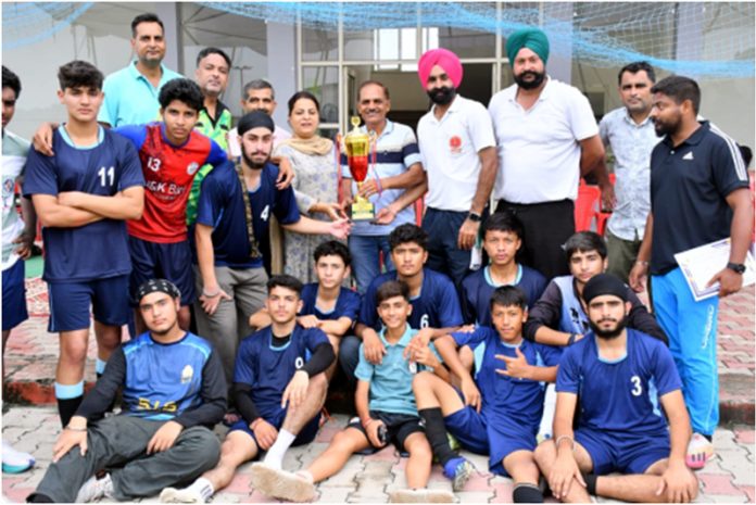 Winning team posing with trophy alongside dignitaries after match presentation ceremony.