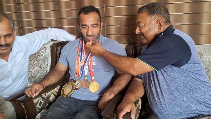 Family members celebrate by offering sweets to Varun Choudhary for his remarkable achievement in Powerlifting.