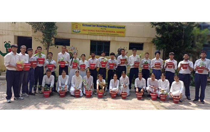 Members of J&K Samaj Kalyan Kendra posing for a group photograph with hearing-impaired students after helping them plant saplings in pots.