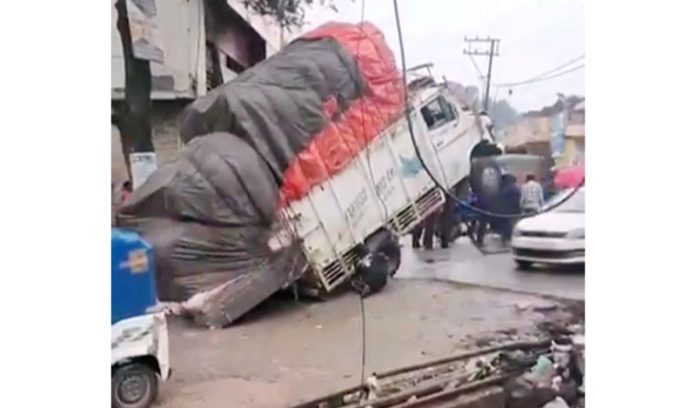 A load carrier traps into damaged ‘puli’ on Rajouri-Thannamandi road near hospital due to recent floods. -Excelsior/Imran