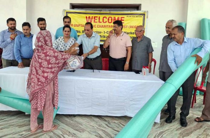 Trustees of T.R Gupta Charitable Trust distributing relief to flood victims at Indira Colony on Wednesday.