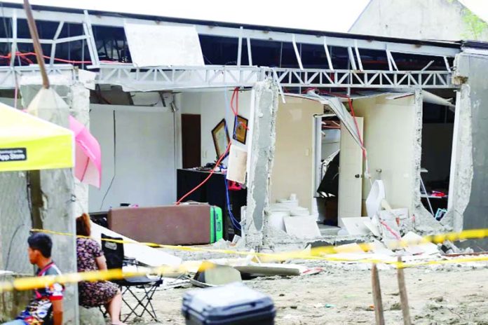 Residents stay besides a damaged house after a strong earthquake in Davao City in Southern Philippines. Residents stay besides a damaged house after a strong earthquake in Davao City in Southern Philippines.