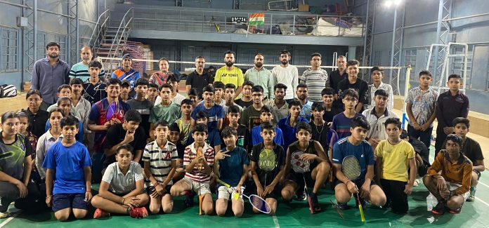 Volleyball players posing along with match officials for a group photograph.