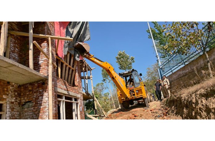 A JCB removing an illegal structure at Hukhar Batkote area of Pahalgam on Monday.
