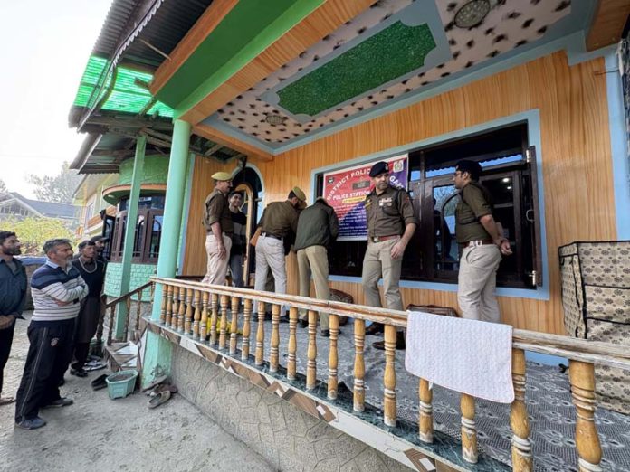 Police personnel pasting an order of attachment over a property in Kulgam district on Wednesday. -Excelsior/Sajad Dar