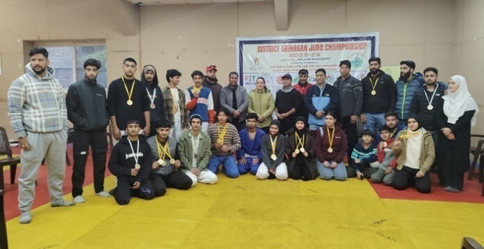 Judo players posing along with medals along with dignitaries.
