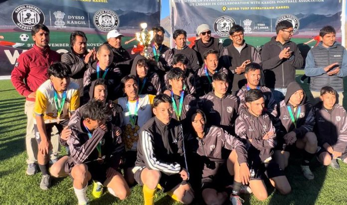Winning team posing along with trophy.