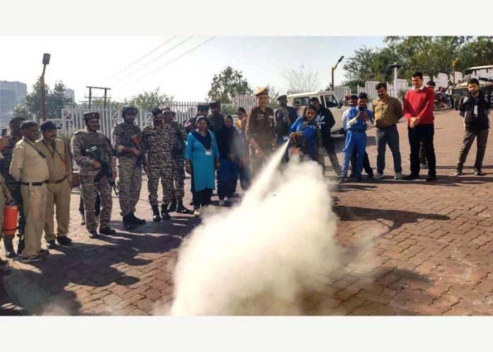 A security personnel demonstrating use of fire extinguisher during a fire safety awareness drive at Tarakote track, Katra.