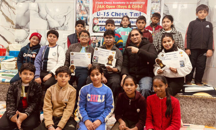 Chess players posing along with trophies.