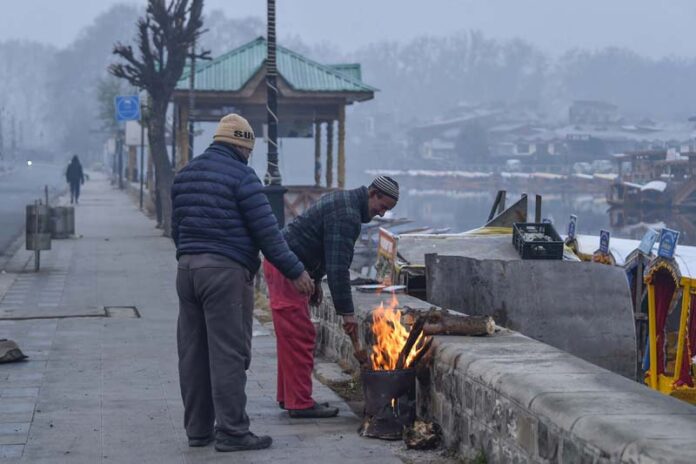 People warm themselves around a fire on Boulevard Road on the banks of Dal lake. -Excelsior/Shakeel
