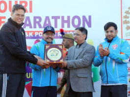 Winner receiving trophy from dignitary during prize distribution ceremony.