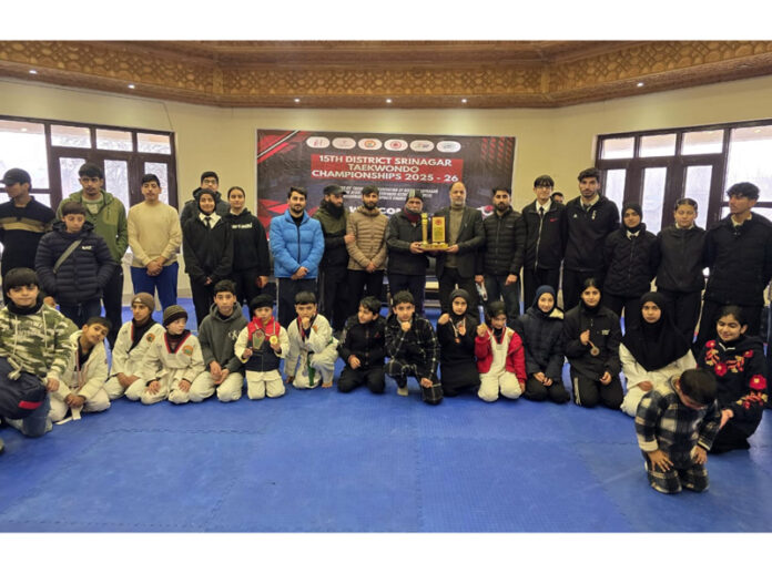 Taekwondo players posing along with medals during prize distribution ceremony.