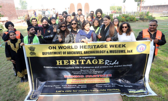 Bike riders led by Sunny Dua posing together at a restored heritage site.