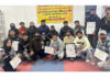 Table Tennis players posing along with certificates and trophies during closing ceremony.