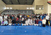 Judo athletes posing along with dignitaries during closing ceremony.
