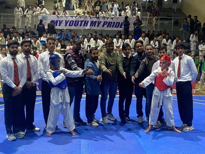 Taekwondo players posing along with dignitaries during event.