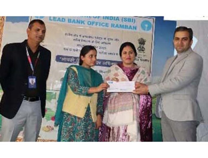 Dignitaries presenting a cheque to a beneficiary under the Aapki Poonji Aapka Adhikar initiative in Ramban district.