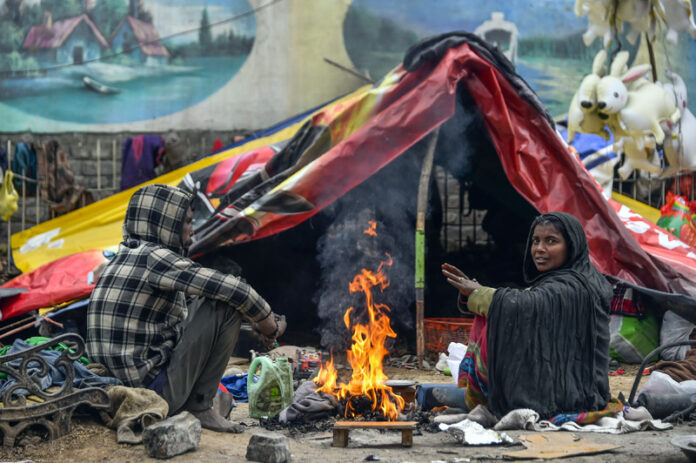 A couple sits outside their makeshift tent, warming their hands over a bonfire on Sunday . —Excelsior/Shakeel