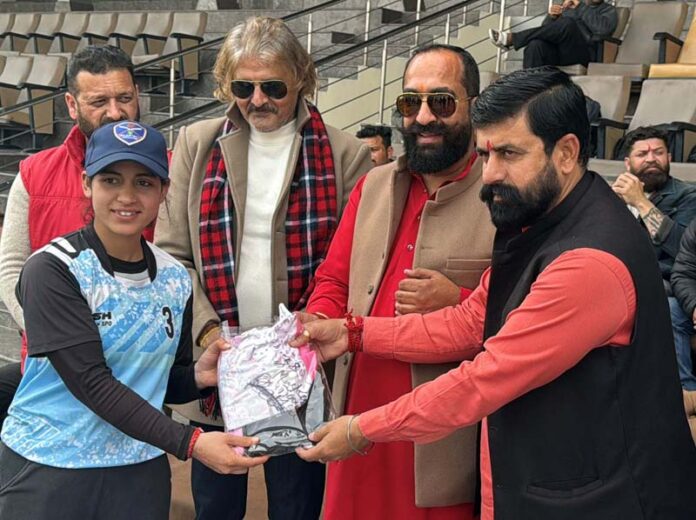 Dignitaries presenting a sports kit to a player during a programme.